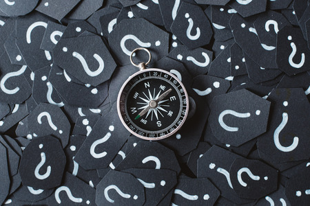 Metal compass on question mark background. Concept of travel, navigation, explore and where to goの写真素材