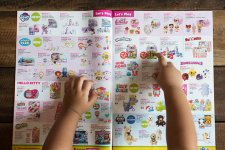 Petaling Jaya, Selangor, Malaysia - 16 March 2019 : Child hand pointing at her dream toy on a TOYS "R"US brochure, asking for a birthday gift. toys r us is a famous company selling toys.のeditorial素材