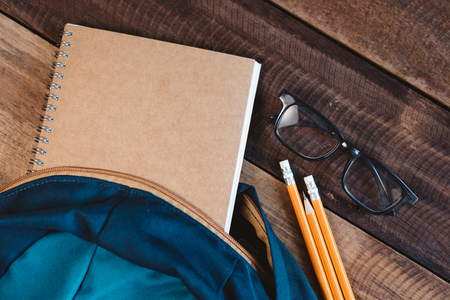 school bag, notebook,pencil,pen and eyeglasses on a wooden table.concept of school equipment and educationの写真素材