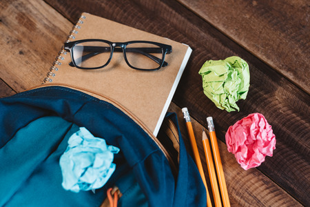 School bag,eyeglasses,pencil,notebook and colorful wrapped paper on a wooden table. concept of school equipment, preparation and educationの写真素材