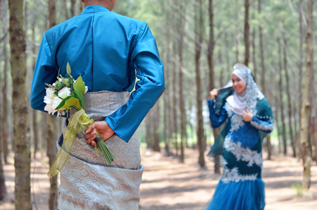 close up of a groom holding a wedding flower bouquet looking at her bride. concept of malay wedding and relationshipの写真素材