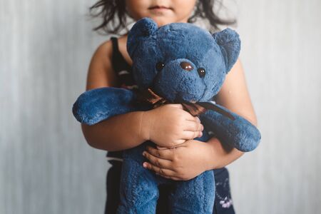 sweet little asian girl hugging her favorite toy teddy bear. Concept of Lonely child, love, childhood and parenting. Selective focus on the plush toy.の写真素材