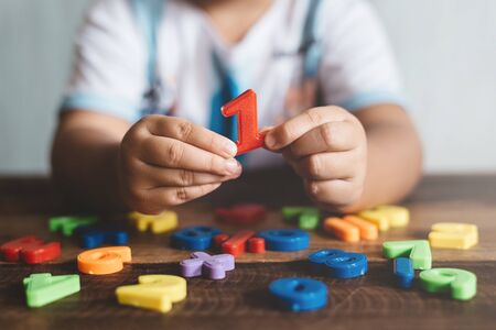 Child holding plastic toy number one, she is learning to count. Concept of child education and child growthの写真素材