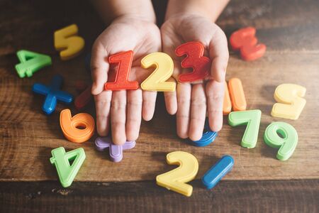 child hands showing a colorful 123 numbers agains wooden table. Concept of Child education, learning mathematics and countingの写真素材