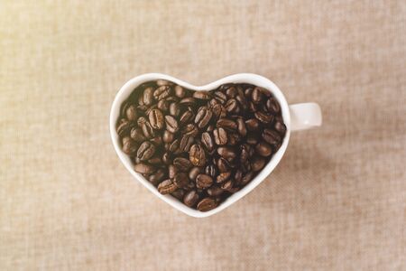 directly above view a heart shape mug of a raw roasted coffee beans. Concept of Favorite drink and coffee addictionの写真素材