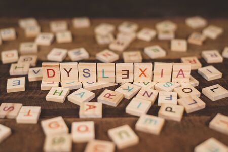 high angle view of a wooden alphabet blocks with DYSLEXIA word in the center on wooden table. Concept of Dyslexia awareness and human brain developmentの写真素材