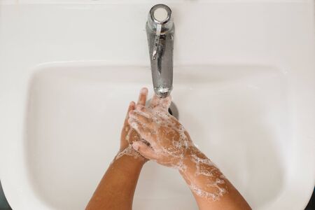 top view of a child washing her hand in washbasin. concept of hand hygiene, health care and global...