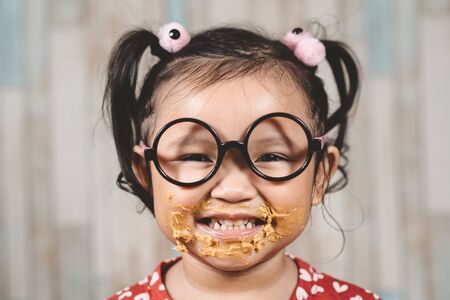 cute little girl with mouth smeared with peanut butter. Concept of penut butter loverの写真素材