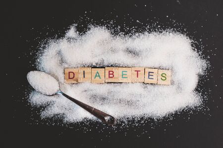 Heap of sugar with word DIABETES on black background. Concept of diabetes, health care and unhealthy eatingの写真素材