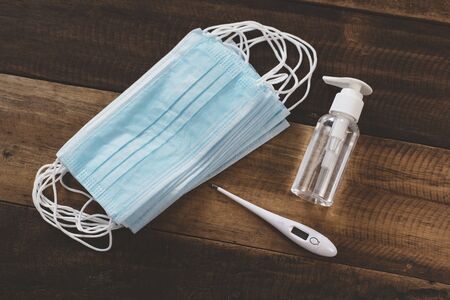 Hand Sanitizer, Surgical Mask and Digital Thermometer on a wooden table. Concept of pandemic, Pollution and health careの写真素材