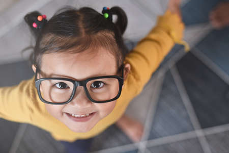 High Angle view of a smiling little asian girl wearing fancy glasses. Concept of happy child and emotionsの写真素材