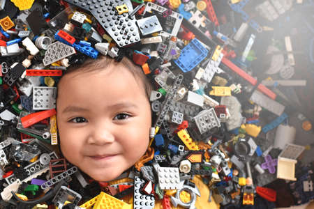 Little asian girl looking at camera surrounded by toy bricks block. Concept of Child developmentの写真素材