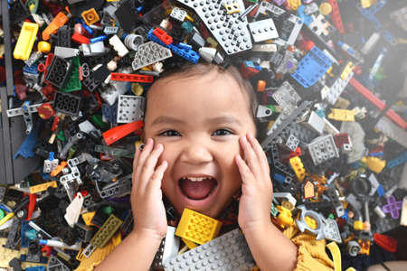 Little asian girl looking at camera surrounded by toy bricks block. Concept of Child developmentの写真素材