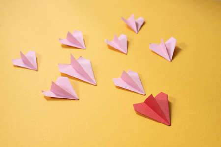 Group of pink paper aeroplane origami following the red one on yellow background. Concept of leadership, teamwork and art craftの写真素材
