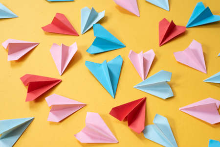 colorful origami paper airplanes on yellow colored background. childhood,freedom, art origami and diversity conceptの写真素材