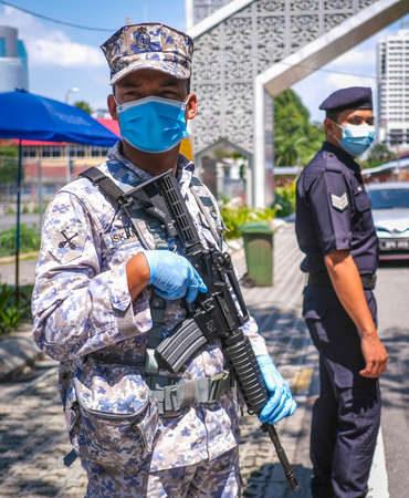 KUALA LUMPUR, MALAYSIA - APRIL 18, 2020 : Malaysia soldier officer inspect road users at a roadblock to enforce the order to stay at home, during the 'movement control order' COVID-19 outbreak.のeditorial素材