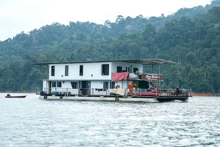 TERENGGANU. MALAYSIA - SEPTEMBER 15, 2019 : Beautiful houseboat crusing through the lake with mountain view at Kenyir Lake. Kenyir Lake also known as Tasik Kenyir, it is the largest man-made lake in South East Asia with an area of 260,000 hectares.のeditorial素材