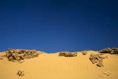 Sand with rocks seen background under dark blue skyの写真素材