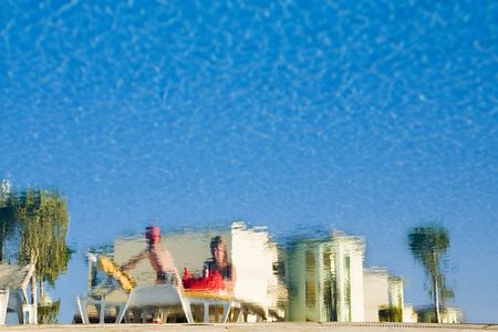 Reflection in pool. The woman and child on sunbed on a background of the dark blue sky.の写真素材