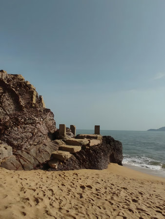 Sandy beach with rocky cliffside and ocean waves