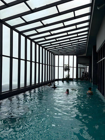 People swimming in an indoor pool with a glass roof and large windows.の写真素材