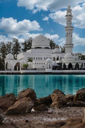 Beautiful white mosque with dome and minaret near a peaceful body of water