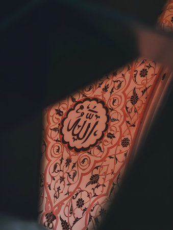 Intricate Arabic script on red patterned cloth with ornate design and blurred background