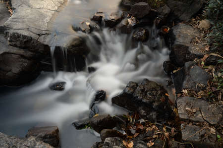 Slow shutter shot of black rocks in a stream