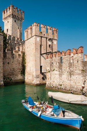 Fisher boat near Scaliger Castle on lake Garda, Sirmione, Italyの写真素材