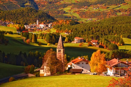 Traditional Tyrol church in alpine valley at autumn sunny day. Dolomites, South Tyrol, Italyの写真素材