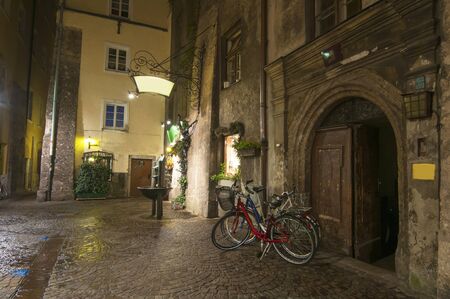 Bicycles parked on empty medieval street in old city of Innsbruck at night, Tirol, Austriaの写真素材