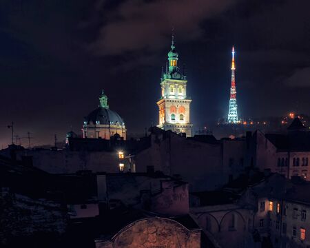 Scenic view of TV tower, Dominican Monastery and Korniakt Tower illuminated at the night over rooftops of old quarters in historical city center of Lviv, Ukraine.の写真素材