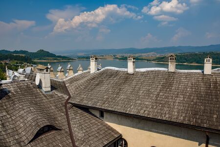 Rooftops and funnels of medieval Niedzica Castle on Dunajec river, Southern Poland. Artificial Czorsztynskie Lake and Pieniny Mountains on background. Niedzica Castle is popular travel destinationの写真素材
