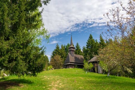 Scenic spring rural landscape with traditional maramures neo-gothic wooden church on background in Maramures - historic region of Romaniaの写真素材