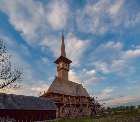 Construction of traditional maramures wooden neo-gothic church in Sapanta village, Romania. Picturesque sky.の写真素材