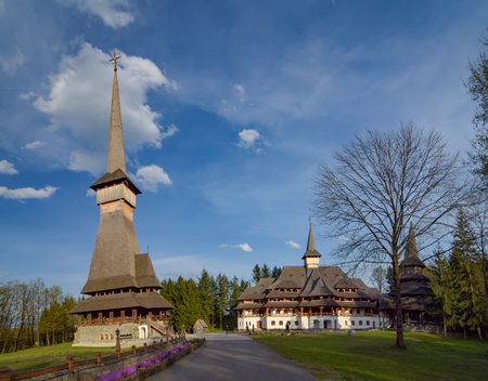 Historical Sapanta-Peri monastery with traditional Maramures neo-gothic wooden church with highest wooden belltower in Europe and monastic cells building, Romania at sunny spring dayの写真素材