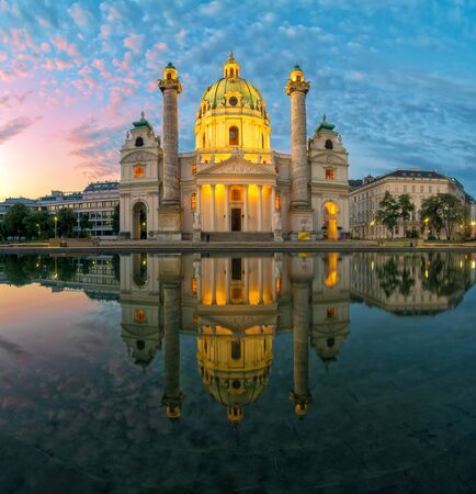 Amazing view of Karlskirche or St. Charles's Church - one of famous churches in Vienna - under picturesque morning sky with illumination and reflection in the water at sunrise, Vienna, Austria.の写真素材