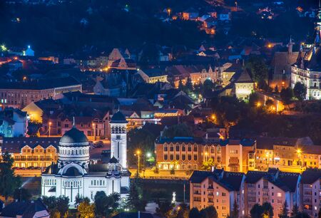 Top panoramic view of illuminated orthodox church and old buildings in downtown of Sighisoara, Transylvania, Romania at night. Birthplace of Vlad Dracula.の写真素材