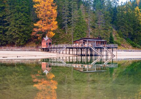 Beautiful autumn alpine landscape, old wooden dock house with pier reflected in wster of Lago di Braies Lake - Pragser Wildsee - Dolomites, Italyの写真素材
