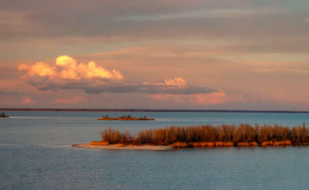 Beautiful clouds illuminated by sunset over Dnieper river near Cherkasy, Ukraine at late autumn eveningの写真素材