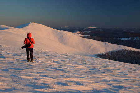 winter mountains landscape on sunset light with reddressed figureの写真素材