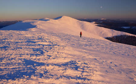 Winter mountains landscape on sunset light with reddressed figure.の写真素材
