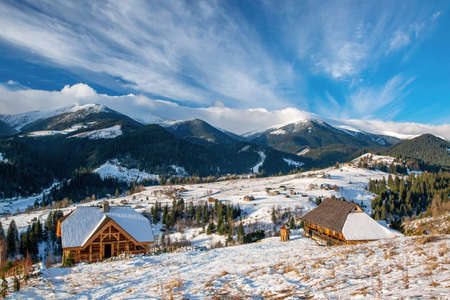 Early spring morning in mountain village. Wooden houses on foreground. Picturesque clouds. Dzembronya, Ukrainian Carpathiansの写真素材