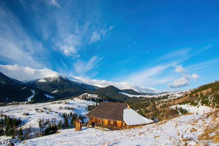 Early spring morning in mountain village. Wooden houses on foreground. Picturesque clouds. Dzembronya, Ukrainian Carpathiansの写真素材