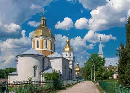 Picturesque view of Orthodox Church of St. Nicholas with golden cupolas and Neo Gothic Roman Catholic Saint Anthony of Padua Church in Strusiv, Ternopil region, Ukraine. Eastern and Western culturesの写真素材