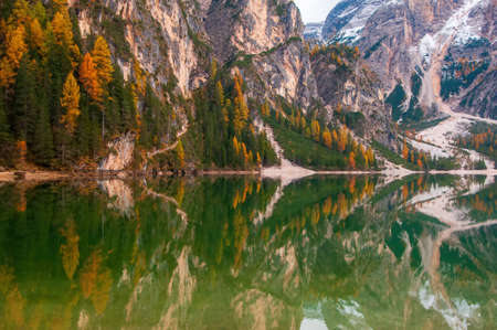 Mountain rocks and autumn forest reflected in water of Braies Lake - Lago di Braies - Pragser Wildsee, Dolomite Alps, Italyの写真素材