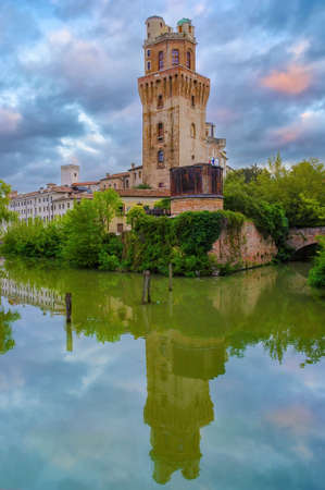 Picturesque view of Torlonga tower reflected in water. Historical Carrara Castle (Castello Carrarese) in Padua (Padova), Veneto, Italy. picturesque burning cloudsの写真素材