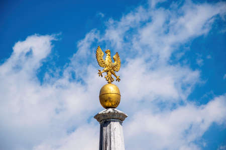 Golden Eagle - Symbol of Kranj, Slovenia on the top of column in Main Square against picturesque skyの写真素材