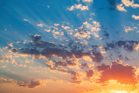 Magnificent sunset on the sky. Sun covered by picturesque cloud with beautiful shine sun beams in the sky. Abstract blue natural background, peaceful skyscape, open heaven and Godの写真素材