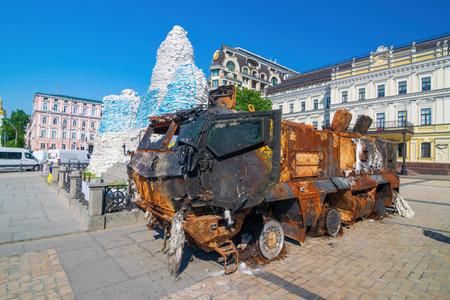 Destroyed russian military armored car during Russian invasion of Ukraine in 2022. Downtown of Kyiv, Ukraine. Monument of the Princess Olga covered with sand bags on backgroundのeditorial素材